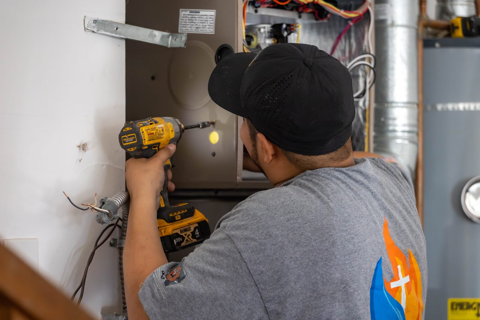 An HVAC Ministries technician in a branded shirt installing a residential gas furnace in a Salem-area home